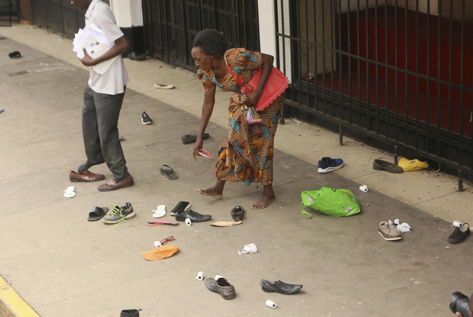 Opposition party supporters pick up their belonging after being surrounded by police officers as they waited to hear a speech by the country's top opposition leader in Harare, Wednesday, Nov. 20, 2019. Zimbabwean police with riot gear fired tear gas and struck people who had gathered at the opposition party headquarters to hear a speech by the main opposition leader Nelson Chamisa who still disputes his narrow loss to Zimbabwean President Emmerson Mnangagwa. (AP Photo/Tsvangirayi Mukwazhi)