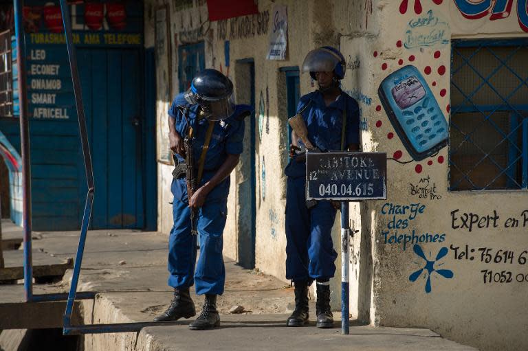 Police officers take cover from stones thrown by protesters in the Cibitoke neighbourhood of Bujumbura on May 5, 2015