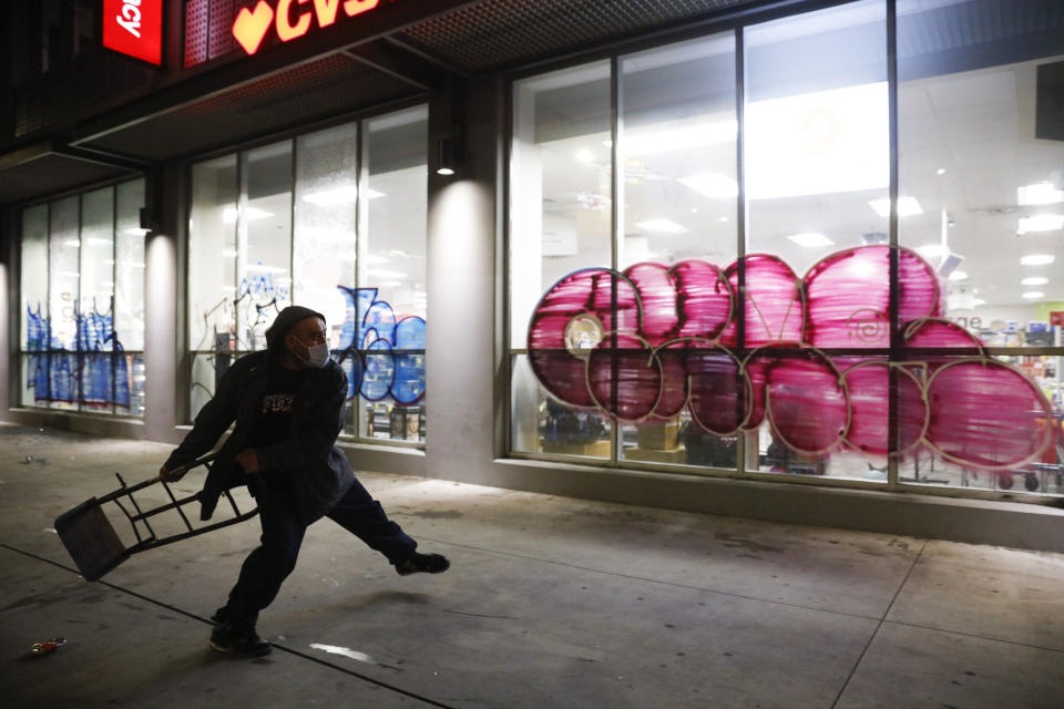 A man throws a hand truck into the window of vandalized CVS store during a protest over the death of George Floyd Saturday, May 30, 2020, in Los Angeles. Floyd died in police custody Monday in Minneapolis. (AP Photo/Jae C. Hong)