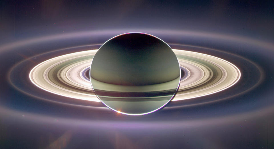 This beautiful image of Saturn and its rings was captured by Cassini's wide angle camera on Sept. 15, 2006. It's a composite of 165 separate pictures and, wouldn't you know it -- Cassini also caught Earth almost a billion miles away visible through the ice and dust of Saturn's rings. Earth is that tiny dot to the left of the rings. The next slide is a close-up of our home.