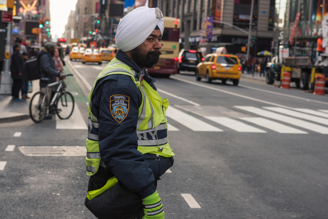 An NYPD traffic officer shown in September 2017 wearing a traditional turban directing traffic. A new settled case will allow officers to grow longer beards and wear navy blue turbans as part of their uniforms in an effort to allow more diversity in the police force. (Photo: Getty Images)