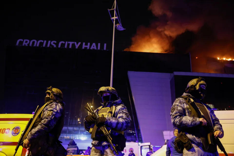 Russian law enforcement officers stand guard near the burning Crocus City Hall concert venue on Friday.