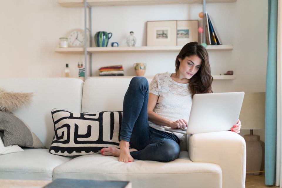 A woman uses a laptop from her sofa