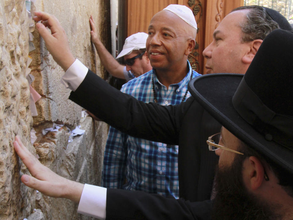 Hip hop mogul Russell Simmons, second left, looks on as US Rabbi Marc Schneier president and founder of the Foundation for Ethnic Understanding (FFEU), second right, and the Western Wall rabbi, Shmuel Rabinovich, right, touch stones of the Western Wall, the holiest site where Jews can pray, in Jerusalem's Old City, Thursday, June 21, 2012. The cofounder of the pioneering Def Jam Recordings record label, which has represented such artists like the Beastie Boys, Jay-Z, Lady Gaga, Jennifer Lopez, LL Cool J and Kanye West, is in Israel on the invitation of Israeli President Shimon Peres.(AP Photo/Blake Sobczak)