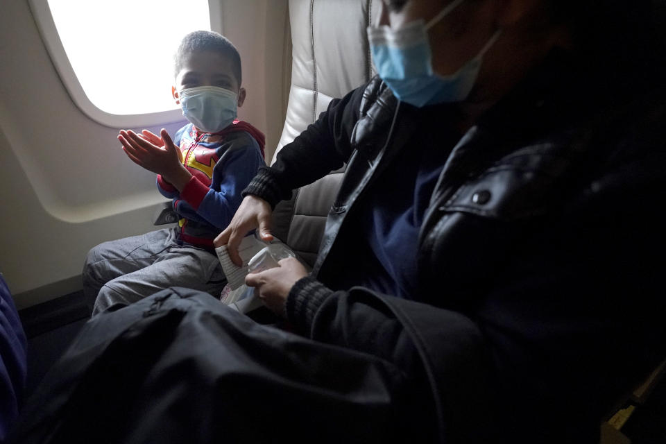 Yancarlos Amaya, 5, left, a migrant from Honduras, claps in excitement as he prepares to ride a plane for the first time with his mother, Celestina Ramirez, at Valley International Airport, Wednesday, March 24, 2021, in Harlingen, Texas. A few days ago Yancarlos was walking along a muddy river bank after crossing the Rio Grande and landing on the U.S. side of the border with Mexico. Ramirez said they turned themselves in to Border Patrol officers and later spent hours in custody, a night under a bridge and three more days in a detention facility. (AP Photo/Julio Cortez)