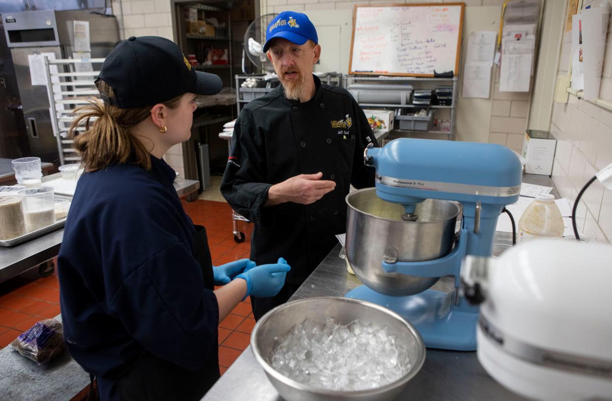 Lancaster High School Culinary Instructor Jeff Cecil (right) talks with junior junior Trinity Reid as she uses a mixer to stirs up buttercream she was making in culinary class on Apr. 17, 2024, in Lancaster, Ohio.