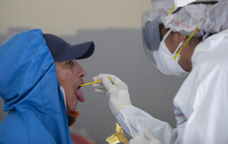 Un trabajador de la salud toma un hisopo para una prueba COVID-19 en el centro de salud El Rosal, en las afueras de La Paz, Bolivia, el domingo 12 de julio de 2020. (AP Foto/Juan Karita)