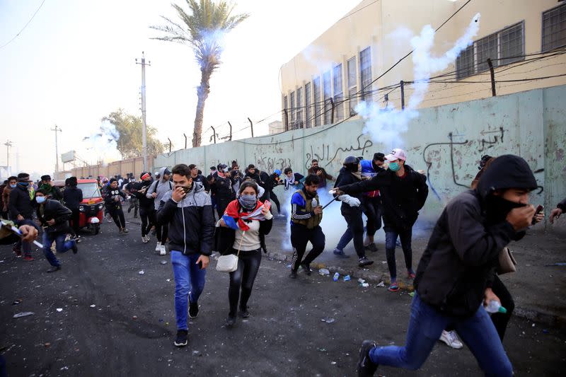 Iraqi demonstrators run from tear gas thrown during ongoing anti-government protests in Baghdad