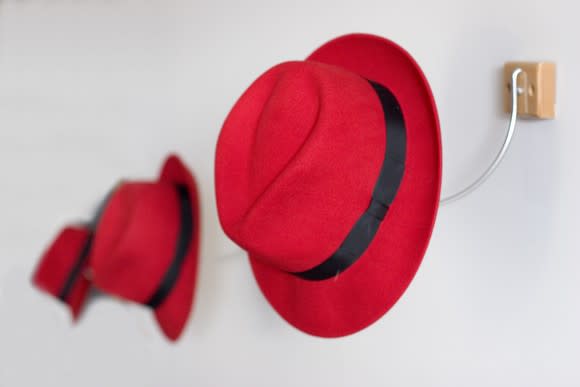 A row of red fedora hats hang on hooks.