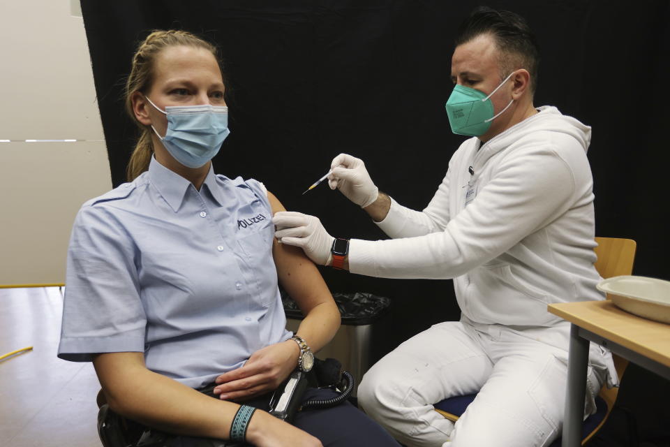 A policewoman gets a booster vaccination against the coronavirus and the COVID-19 disease in Hilden, Germany, Thursday, Dec. 2, 2021. Germany's outgoing Chancellor Angela Merkel and her likely successor met with state governors to consider tighter rules to curb coronavirus infections. The rise in COVID-19 cases over the past weeks and the arrival of the new omicron variant have prompted warnings from scientists and doctors that medical services in the country could become overstretched in the coming weeks unless drastic action is taken. (David Young/dpa via AP)