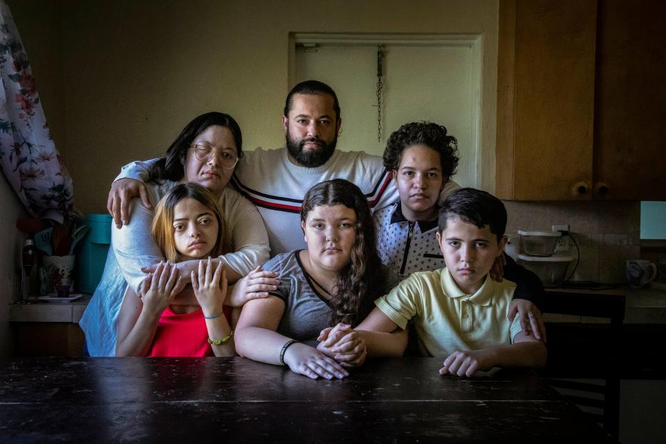 The Torres/Medina family, from left: Raysa Torres (mother), Iriana (daughter), 17, Nelson Torres Sr. (father), Janelliz (daughter, center), 13, Anaya Rodriguez (niece), 15, and Nelson Jr., (son), 11, sit around the kitchen table of their rental home in Palm Springs. Debilitating tumors affecting the brain and spine continue to plague Raysa, Iriana and Anaya.