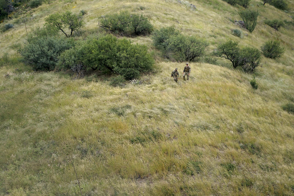 A 38-year-old man from Mexico City, left, is helped down a mountain by Daniel Bolin, a search, trauma and rescue agent with the U.S. Border Patrol, right, Thursday, Sept. 8, 2022, near Sasabe, Ariz. The migrant called 911 after nearly dying atop Baboquivari Peak after developing debilitating foot blisters with no food or water. The desert region located in the Tucson sector just north of Mexico is one of the deadliest stretches along the international border with rugged desert mountains, uneven topography, washes and triple-digit temperatures in the summer months. Border Patrol agents performed 3,000 rescues in the sector in the past 12 months. (AP Photo/Giovanna Dell'Orto)