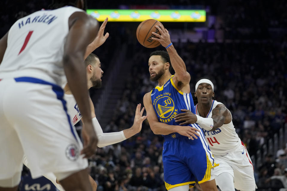 Golden State Warriors guard Stephen Curry (30) passes the ball while defended by Los Angeles Clippers guard Terance Mann, right, and center Ivica Zubac during the first half of an NBA basketball game Thursday, Nov. 30, 2023, in San Francisco. (AP Photo/Godofredo A. Vásquez)