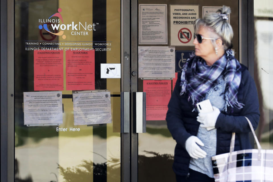 A woman looks to get information about job application in front of IDES (Illinois Department of Employment Security) WorkNet center in Arlington Heights, Ill., Thursday, April 9, 2020. Another 6.6 million people filed for unemployment benefits last week, according to the US Department of Labor, as American workers continue to suffer from devastating job losses, furloughs and reduced hours during the coronavirus pandemic. (AP Photo/Nam Y. Huh)