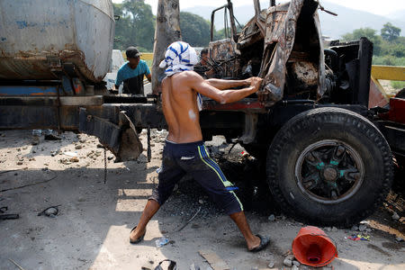 People dismantle a truck that was burnt during clashes between opposition supporters and Venezuela's security forces, on the Simon Bolivar cross-border bridge between Venezuela and Colombia, in Cucuta, Colombia February 24, 2019. REUTERS/Marco Bello