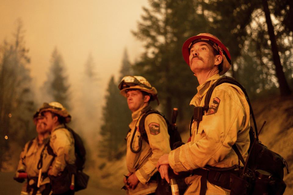 Cal Fire Capt. Dom Kaska, right, monitors flames as his crew burns vegetation to stop the Dixie Fire from spreading near Prattville in Plumas County, Calif., on Friday, July 23, 2021. (AP Photo/Noah Berger)