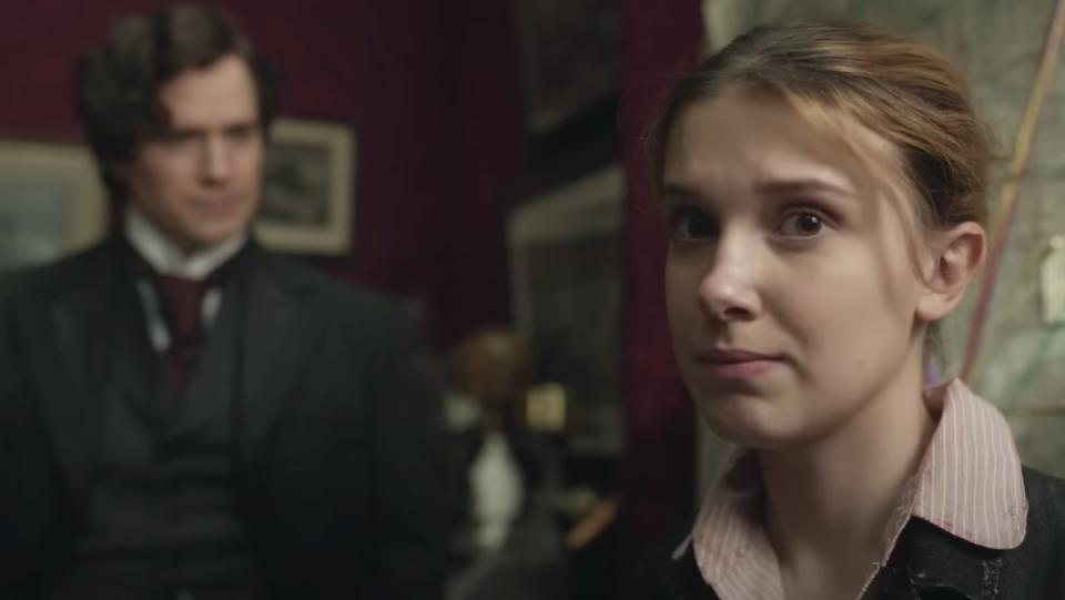 Millie Bobby Brown's Enola Holmes looks at the camera while standing inf ront of her brother Sherlock in Enola Holmes 2