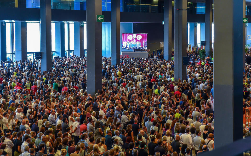 A crowd of people attends the funeral service of some of the victims of a collapsed highway bridge, in Genoa's exhibition center Fiera di Genova, Italy, Saturday, Aug. 18, 2018. Saturday has been declared a national day of mourning in Italy and includes a state funeral at the industrial port city's fair grounds for those who plunged to their deaths as the 45-meter (150-foot) tall Morandi Bridge gave way Tuesday. (Simone Arveda/ANSA via AP)