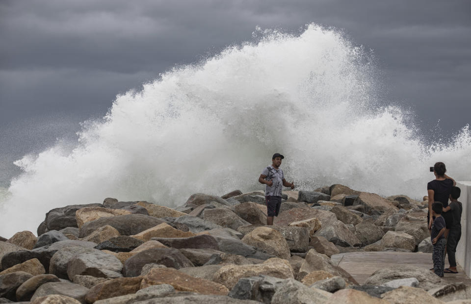 A tourist poses for a photo in front breaking waves before the expected arrival of Hurricane Lorena, in Los Cabos, Mexico, Friday, Sept. 20, 2019. Hurricane Lorena neared Mexico's resort-studded Los Cabos area Friday as owners pulled their boats from the water, tourists hunkered down in hotels, and police and soldiers went through low-lying, low-income neighborhoods urging people to evacuate. (AP Photo/Fernando Castillo)