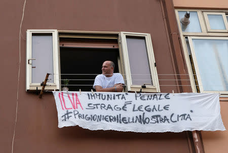 Cosimo Briganti, a worker of the ILVA steel plant, hangs an homemade sign reading "Ilva. Criminal impunity = legal massacre - Prisoners in our city" in Taranto, southern Italy June 14, 2018. Picture taken June 14, 2018. REUTERS/Crispian Balmer