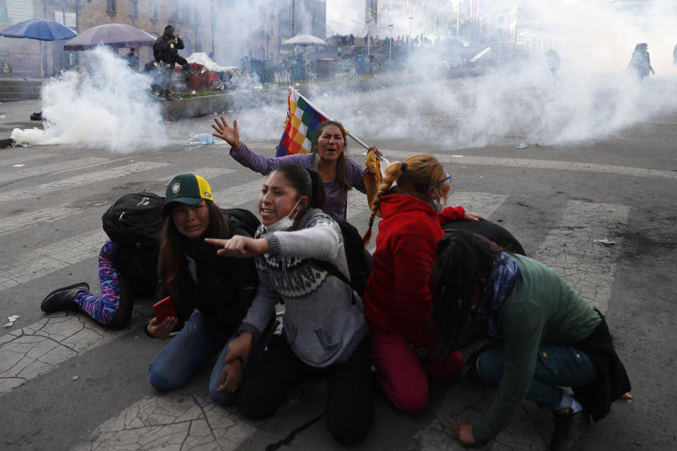 Supporter of former President Evo Morales protect themselves from tear gas launched by the police, in La Paz, Bolivia, Nov. 15, 2019. (AP Photo/Natacha Pisarenko)