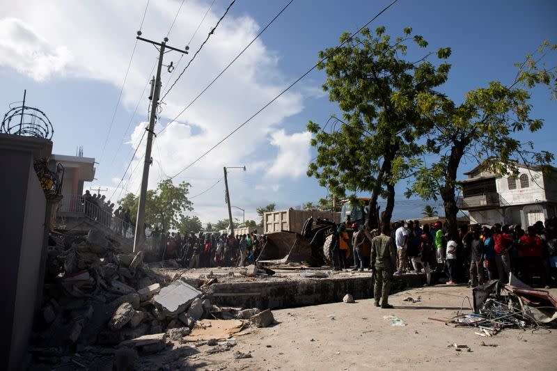 People look at a damaged house after a 7.2 magnitude earthquake in Les Cayes