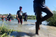 Migrants find an alternate place to cross between Mexico and the United States after access to a dam was closed, Sunday, Sept. 19, 2021, in Ciudad Acuña, Mexico. U.S. officials said that within the next few days, they plan to ramp up expulsion flights for some of the thousands of Haitian migrants who have gathered in the Texas city from across the border in Mexico. (AP Photo/Sarah Blake Morgan)