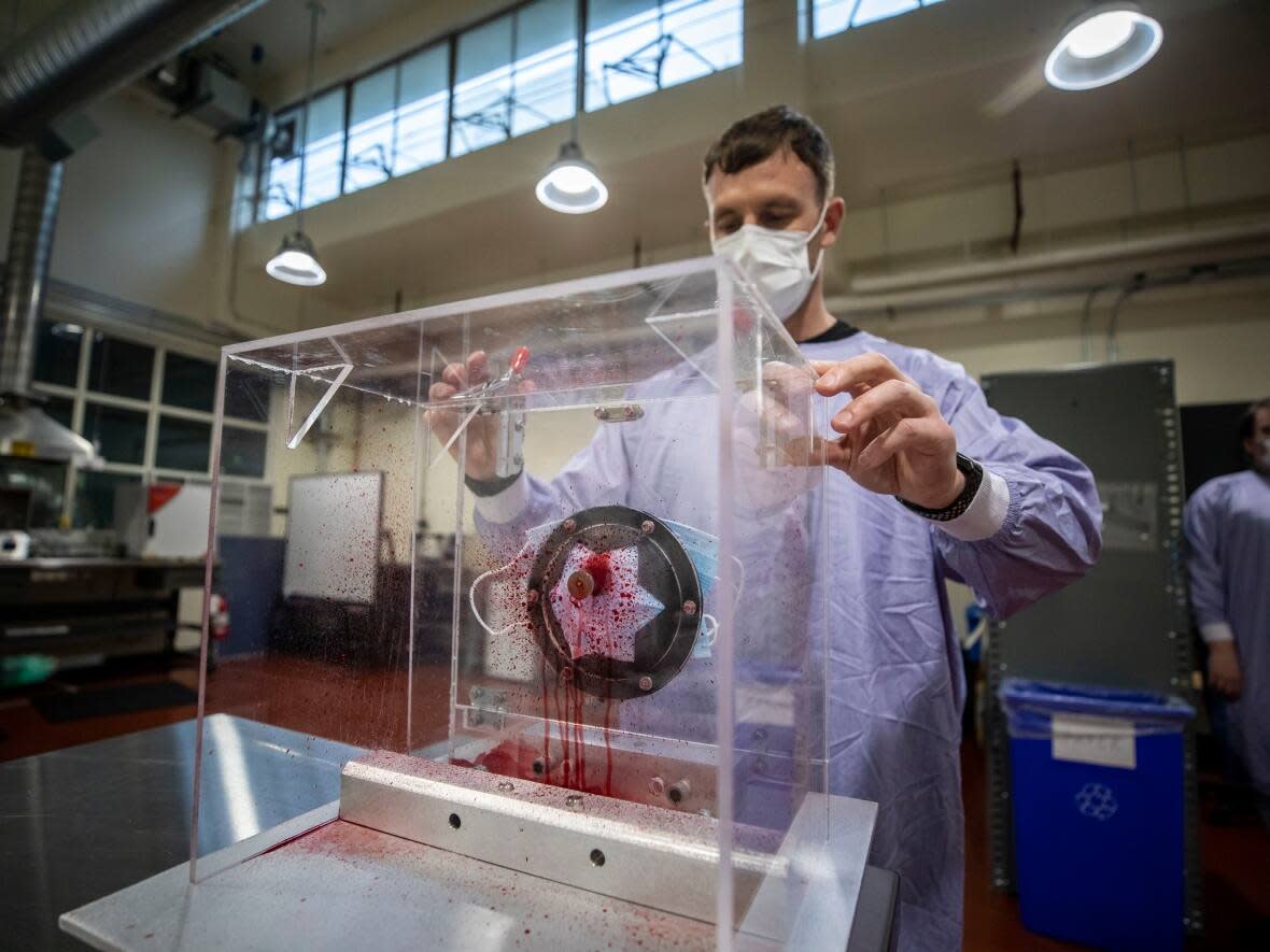 Lab manager Jesse Cooper performs a resistance-to-penetration-by-synthetic-blood test on a surgical mask in the PPE Testing Lab at the Vancouver General Hospital in Vancouver, British Columbia on Friday, Oct. 22, 2021.  (Ben Nelms/CBC - image credit)