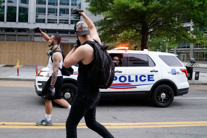 Protesters march past a police car during a protest against the death in police custody of George Floyd