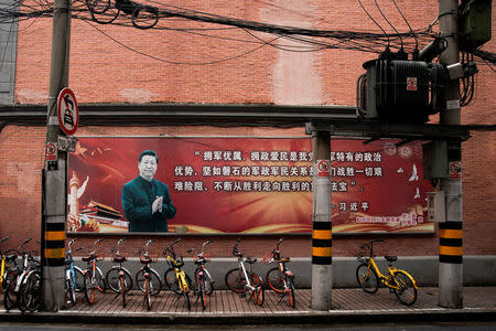 Rental bikes are parked underneath a portrait of Chinese President Xi Jinping in Shanghai, China, September 26, 2017. The slogan reads: "The government and the people should support the military and give preferential treatment to the families of servicemen and martyrs, and the military supports the government and cherishes the people. It has long been a good tradition and a unique political advantage for the Party, army and people. It is of extreme importance to consolidate the solidarity between the military and the government and between the military and the people." Picture taken September 26, 2017. REUTERS/Aly Song