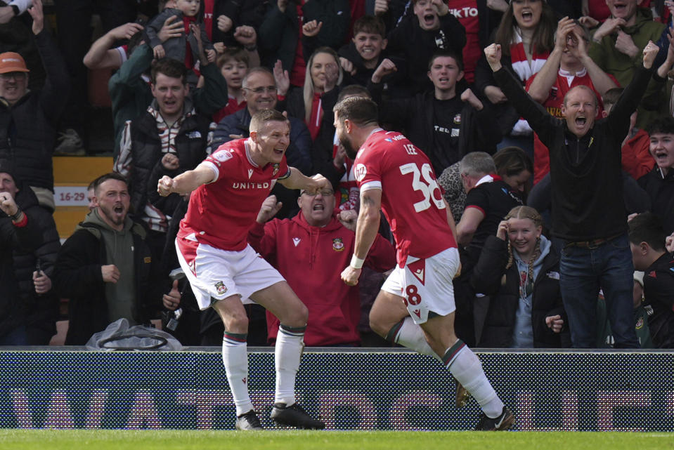 Wrexham's Elliot Lee, right, celebrates with Paul Mullin after scoring their side's first goal of the game during the Sky Bet League Two match at the SToK Cae Ras, Wrexham, England, Saturday April 13, 2024. (Jacob King/PA via AP)