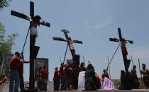 A Filipino devotee who was nailed to a cross is lifted as they try to re-enact the crucifixion of Jesus Christ in San Juan village, Pampanga province, northern Philippines on Friday, April 18, 2014. Church leaders and health officials have spoken against the practice which mixes Roman Catholic devotion with folk belief, but the annual rites continue to draw participants and huge crowds. (AP Photo/Aaron Favila)