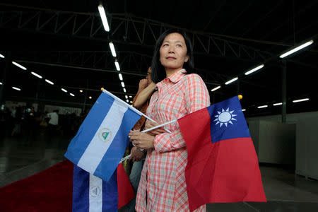 A Taiwanese citizen living in Managua holds Nicaragua's flag and Taiwan's flag as she waits for arrival of Tawain's President Tsai Ing-wen at the textile industrial park in Managua, Nicaragua January 10, 2017. REUTERS/Oswaldo Rivas