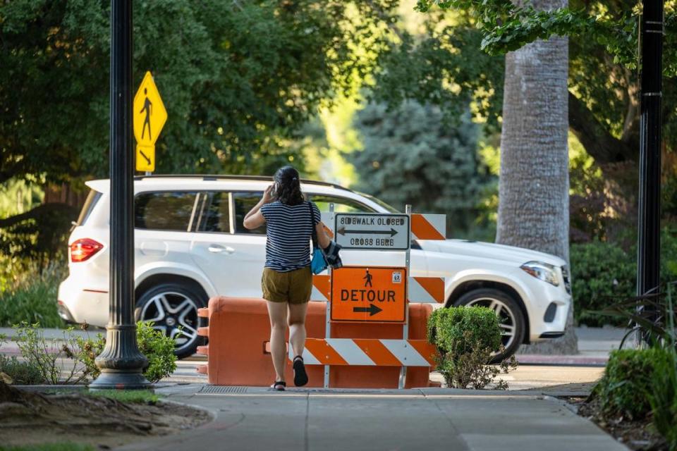 A pedestrians waits to cross through the sidewalk closure at 14th and N streets closed by the City during the Capitol construction in downtown Sacramento on June 28, 2024.