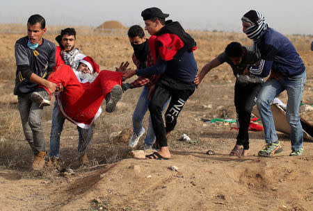 A wounded Palestinian demonstrator dressed as Santa Claus is evacuated during clashes with Israeli troops, at a protest as Palestinians call for a "Day of Rage" in response to U.S. President Donald Trump's recognition of Jerusalem as Israel's capital, near the border with Israel in the southern Gaza Strip. REUTERS/Ibraheem Abu Mustafa
