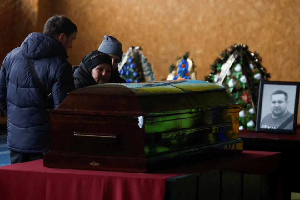 People stand next to the coffin duing the funeral ceremony of Mykhailo Korenovskyi, Ukrainian boxing coach and a father of two, killed during the Russian missile attack in Dnipro, Ukraine, on January 17, 2023.