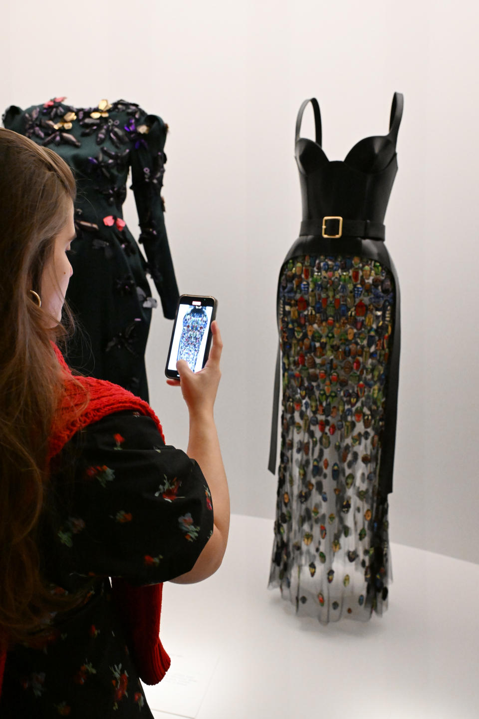 Woman takes photo of two dresses on display with her phone