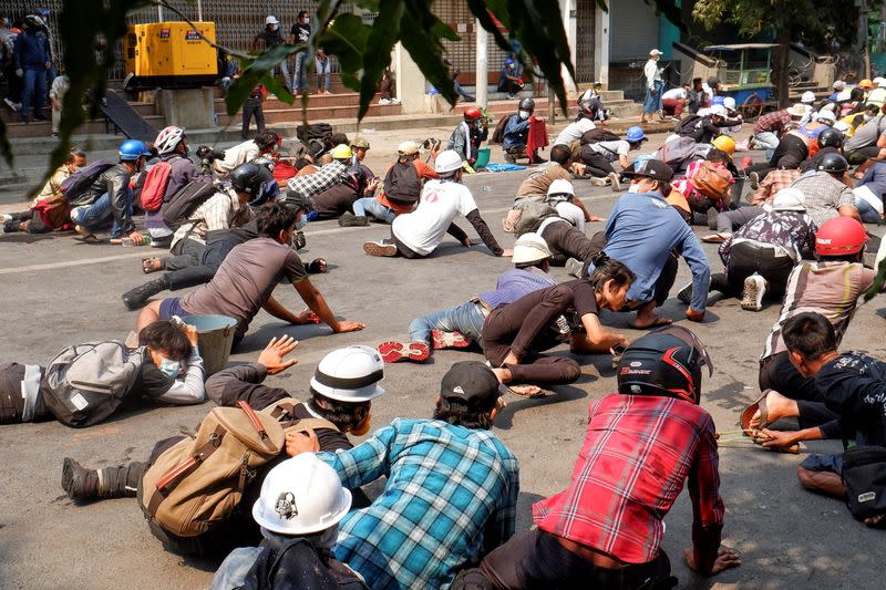 Protesters lie on the ground after police open fire to disperse an anti-coup protest in Mandalay, Myanmar