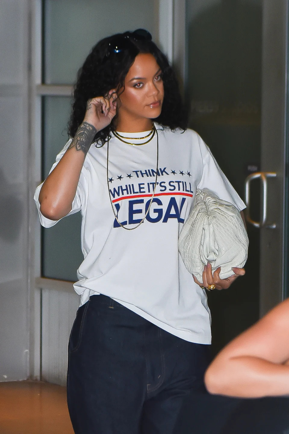 Rihanna touches her ear while carrying a purse