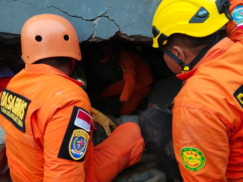 Members of a search and rescue agency team dig through rubble after an earthquake, in Mamuju