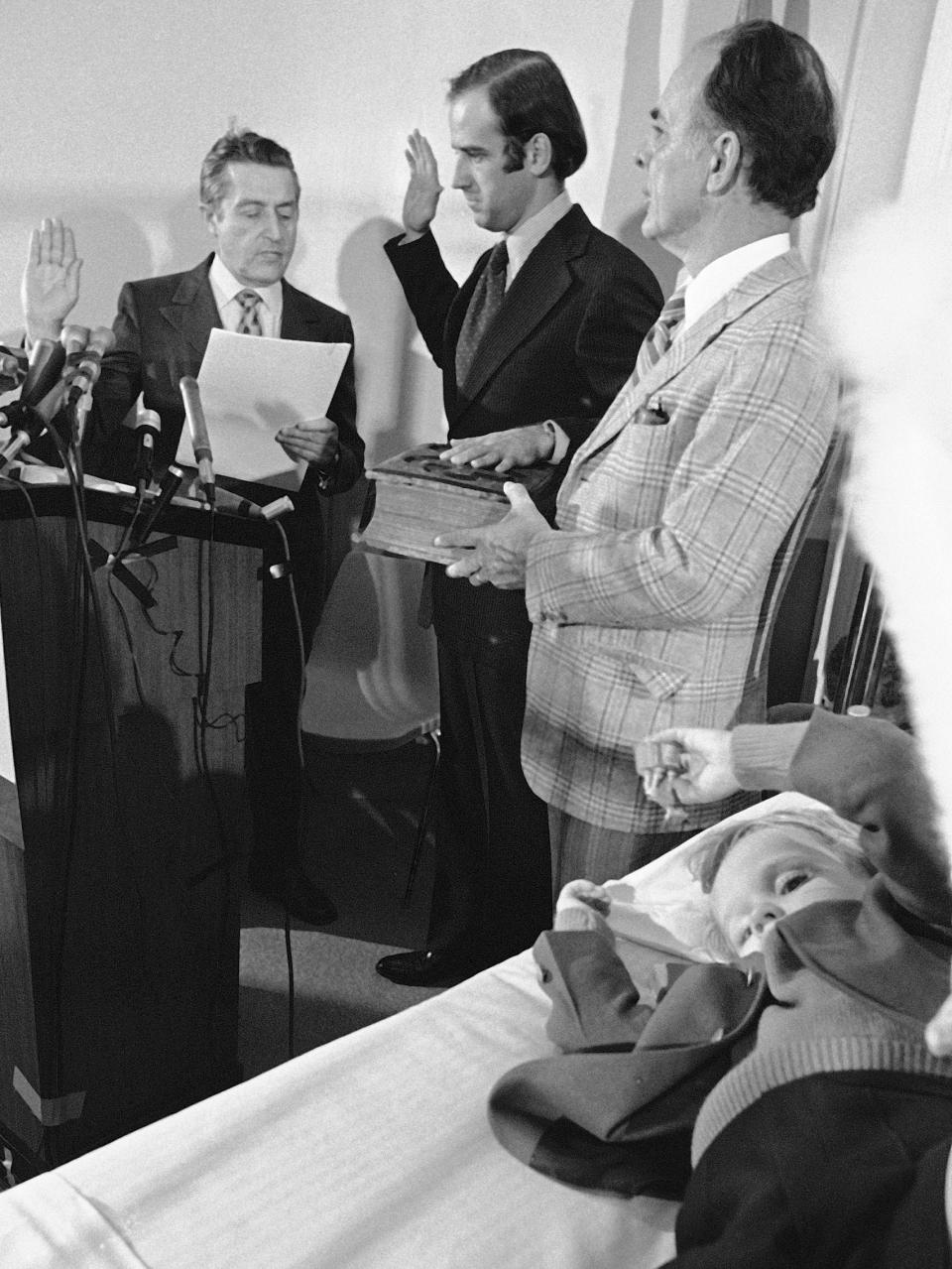 FILE - In this Jan. 5, 1973 file photo, four-year-old Beau Biden, foreground, plays near his father, Joe Biden, center, being sworn in as the U.S. senator from Delaware, by Senate Secretary Frank Valeo, left, in ceremonies in a Wilmington hospital. Beau was injured in an accident that killed his mother and sister in December 1972. Biden's father, Robert Hunter, holds the Bible. (AP Photo/File)