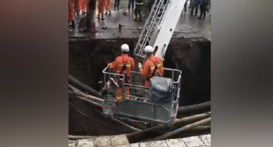 Workers in the sinkhole (pictured) in Dazhou, Sichuan, China