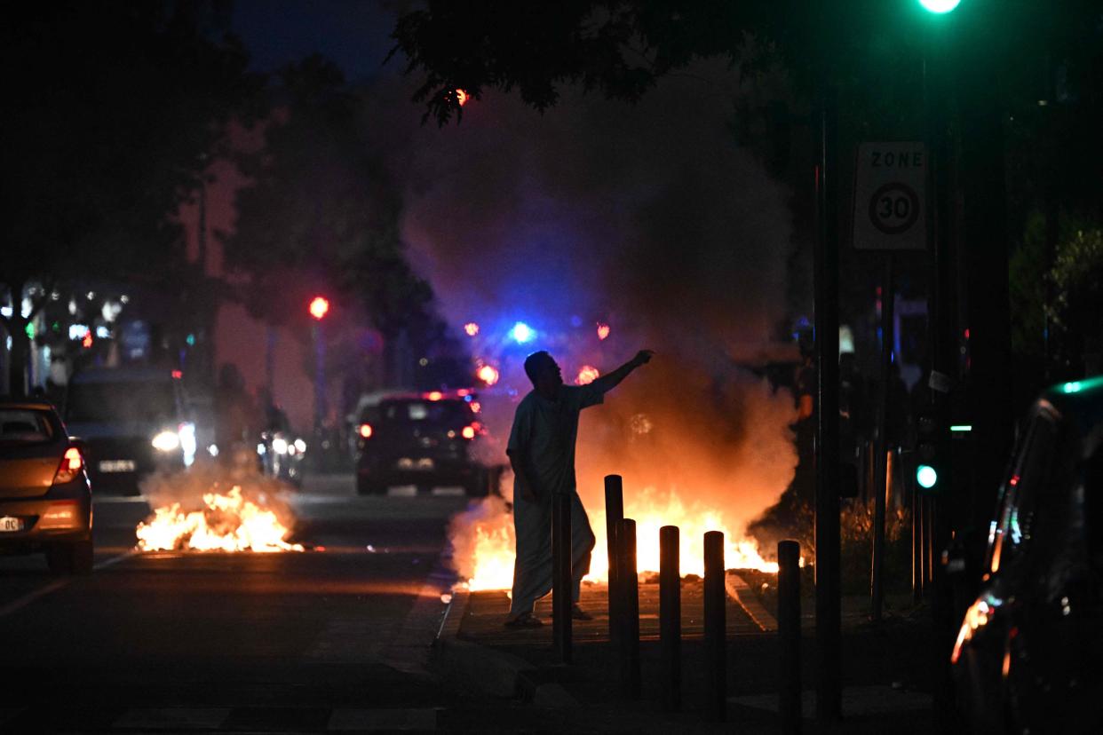 A man walks past a bonfire in a residential area during clashes in Toulouse, southwestern France on 28 June 2023 (AFP via Getty Images)