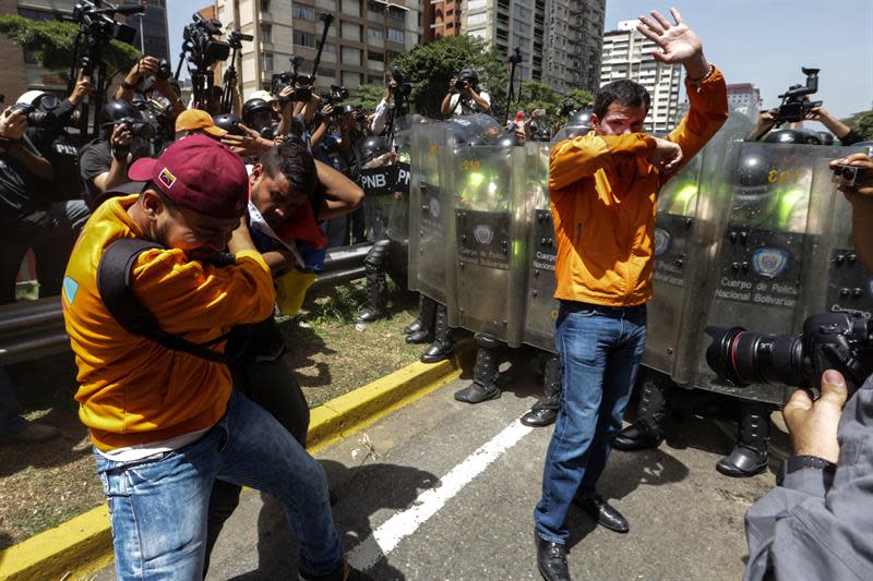 <p>El diputado José Guaidó (d) es afectado por gas lacrimógeno frente a integrantes de la Policía Nacional Bolivariana (PNB) durante una manifestación hoy, martes 4 de abril de 2017, que intentaba marchar hacia el Parlamento en apoyo a la destitución de los magistrados del Supremo, en Caracas (Venezuela). La Guardia Nacional Bolivariana de Venezuela (GNB, policía militar) disolvió hoy con gases lacrimógenos y perdigones de goma una manifestación de decenas de opositores. EFE/CRISTIAN HERNÁNDEZ </p>