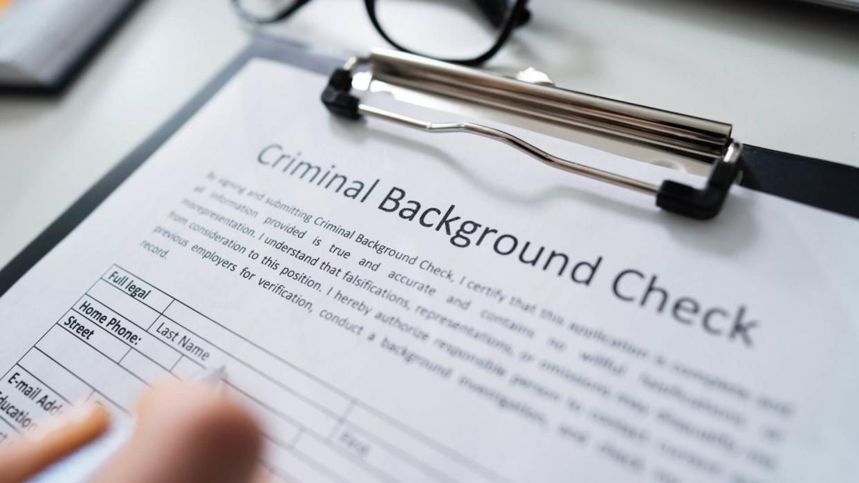 Close-up Of Human Hand Filling Criminal Background Check Application Form With Pen.