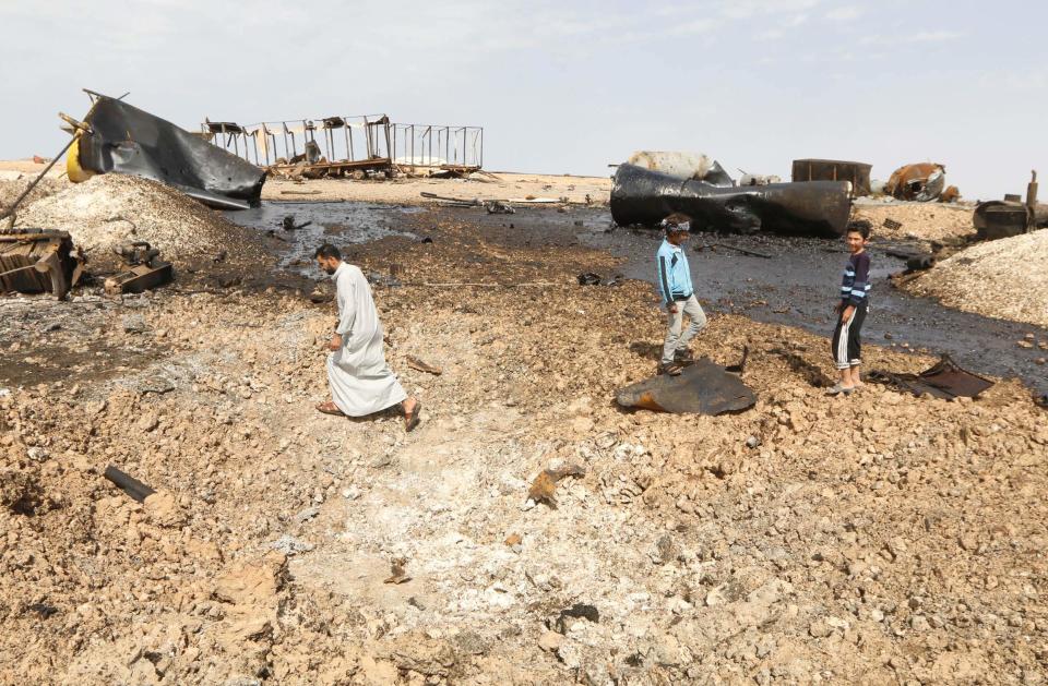 People inspect damage at an oil refinery that was targeted by what activists said were U.S.-led air strikes at al-Khaboura village, near the Syrian town of Tel Abyad of Raqqa governate October 2, 2014. Air strikes believed to have been carried out by U.S.-led forces hit three makeshift oil refineries in Syria's Raqqa province early on Sunday as part of an assault to weaken Islamic State (IS) militants, a human rights group said. The United States has been carrying out strikes in Iraq against the Islamic State since July and in Syria since last week with the help of allies. Using mostly nighttime strikes, it aims to damage and destroy the bases and forces of the al Qaeda offshoot which has captured large areas of both countries. REUTERS/Stringer (SYRIA - Tags: POLITICS CIVIL UNREST ENERGY TPX IMAGES OF THE DAY)