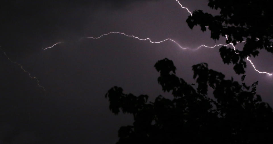 Lightning crosses the sky above trees in Lawrence, Kan., Thursday, May 8, 2014. The area is under a severe thunderstorm watch. (AP Photo/Orlin Wagner)