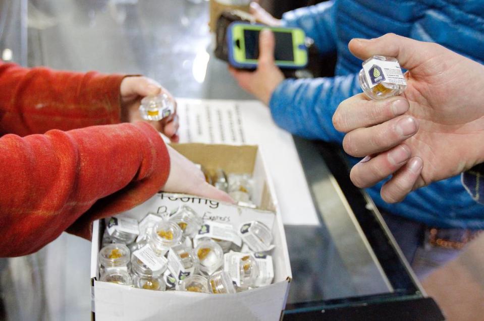 Budtender Ashley Stanley, left, shows customers some hash oil at Evergreen Apothecary in Denver.