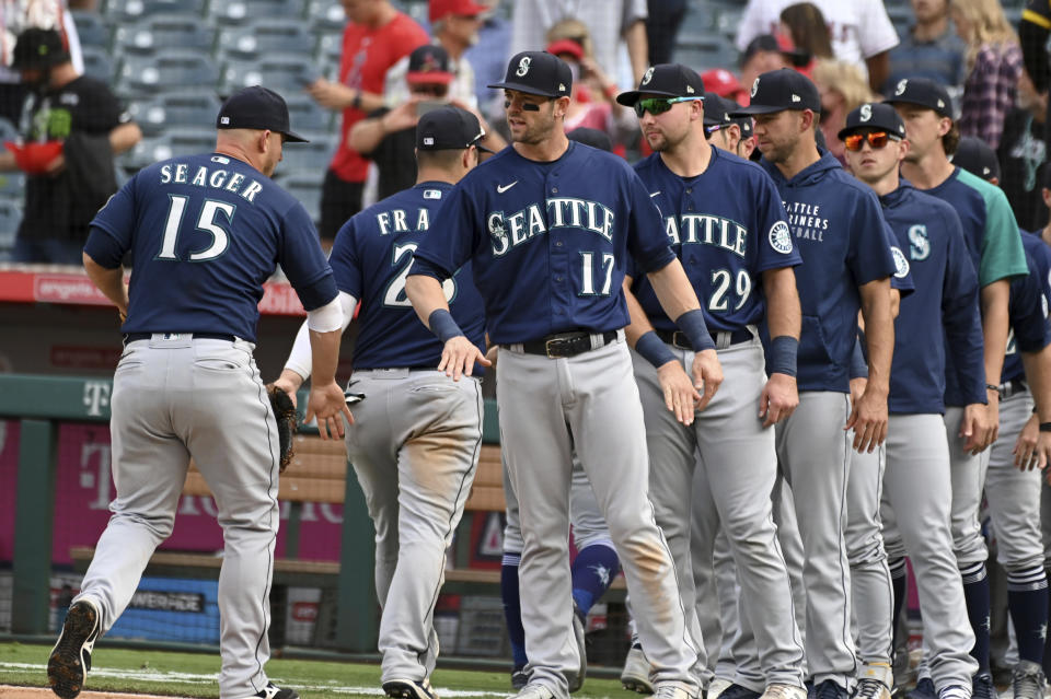 Seattle Mariners' Kyle Seager (15) is congratulated by Mitch Haniger (17) and teammates after beating the Los Angeles Angels 5-1, Sunday, Sept. 26, 2021, in Anaheim, Calif. (AP Photo/Michael Owen Baker)