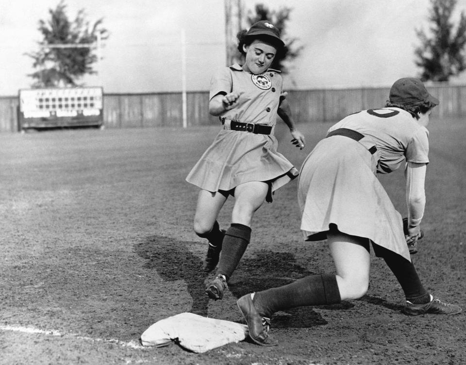 A woman of the All-American Girls Professional Baseball League steps on a base.